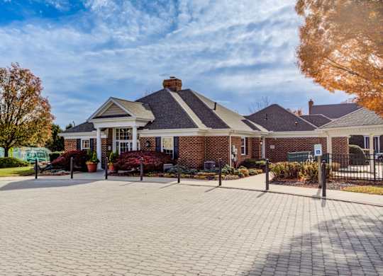 A brick building with a black roof and a sign on a post at Highlands at Warwick Apartments, Lilitz, Pennsylvania