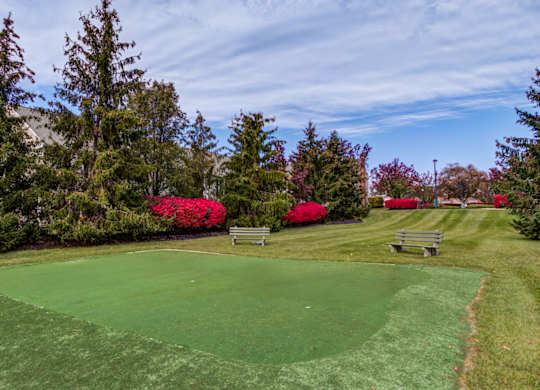 A green lawn with a red bush and a bench at Highlands at Warwick Apartments, Pennsylvania