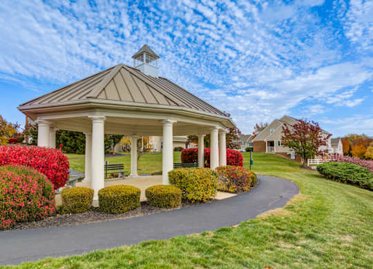 A gazebo is surrounded by red flowers and green grass at Highlands at Warwick Apartments, Lilitz, Pennsylvania