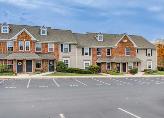 A large brick building with a parking lot in front at Highlands at Warwick Apartments, Lilitz, PA 17543