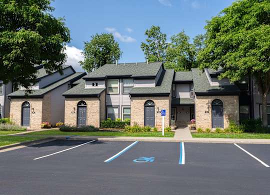 A parking lot in front of a building with a blue handicap sign painted on the pavement.