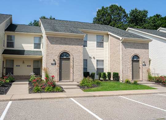 A row of houses with a parking lot in front.