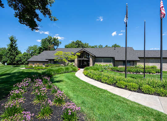 A building with a flag on top and a garden in front.