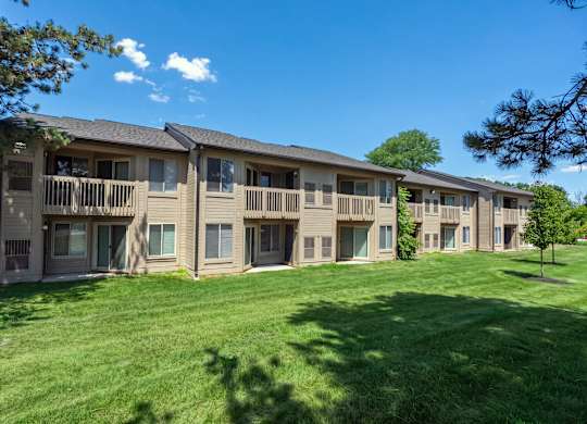 A row of apartment buildings with green lawns in front.
