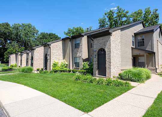 A row of houses with a sidewalk in front.