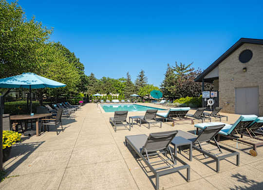 A sunny day at the poolside with chairs and umbrellas.
