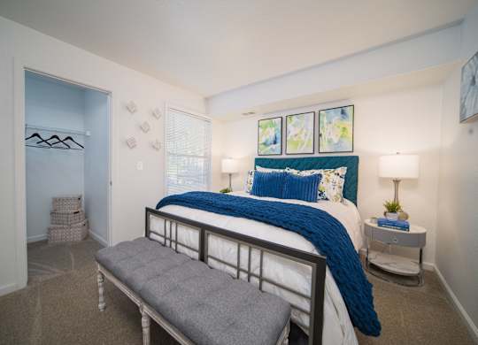 A bedroom with a bed, bench, and two lamps.