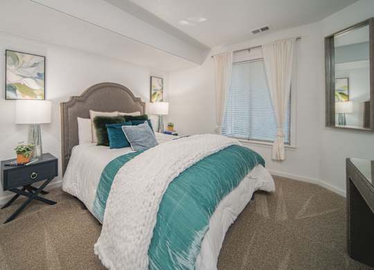 A bedroom with a large bed and a mirror on the wall.