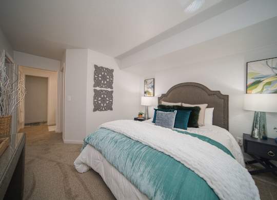 A bedroom with a large bed and a nightstand with a lamp.