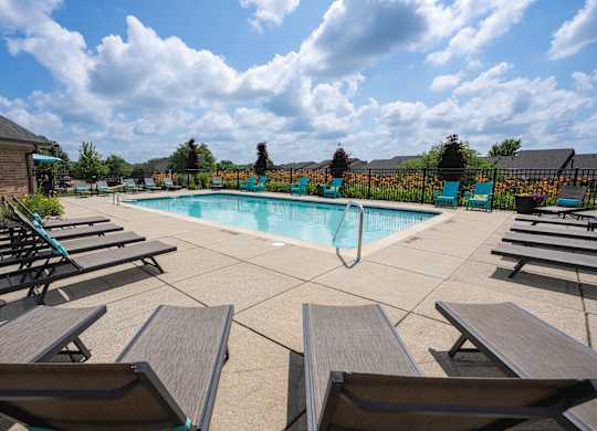A pool surrounded by wooden benches on a sunny day.