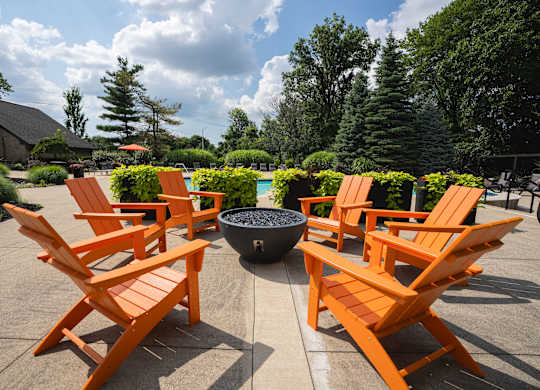 A set of orange chairs are arranged around a fire pit.