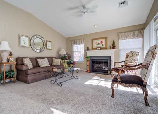 A living room with a fireplace, a sofa, a chair, and a table with a lamp at The Crest at Elm Tree, Mount Joy