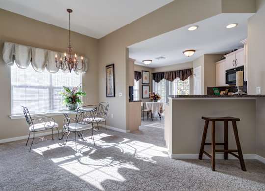 A sunny day in a well-lit living room with a dining table and chairs at The Crest at Elm Tree, Pennsylvania