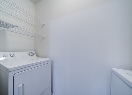 A white dryer is in a small room with a white wall at The Crest at Elm Tree, Mount Joy, PA
