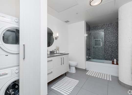 A modern bathroom with a washing machine built into the cabinetry.