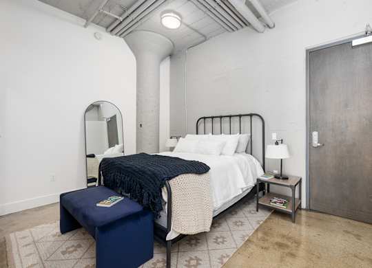 A bedroom with a bed, a bench, and a lamp.