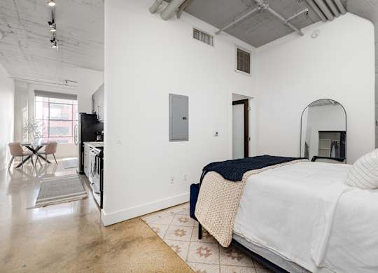 A bedroom with a bed, a chair, and a mirror.