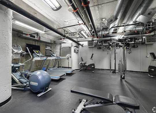 A gym with a variety of equipment including treadmills, exercise balls, and weight machines.