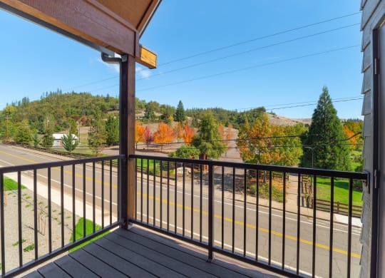 the view from the balcony of a house overlooking a street and trees