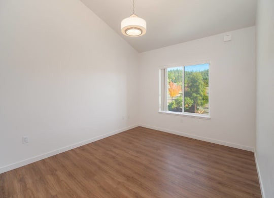 an empty living room with wood floors and a window