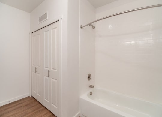a bathroom with a white tub and shower and a white door