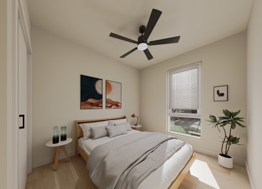 A bedroom with a bed, a ceiling fan, and a potted plant.