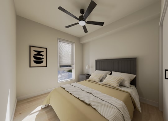 A bedroom with a bed, a ceiling fan, and a window.