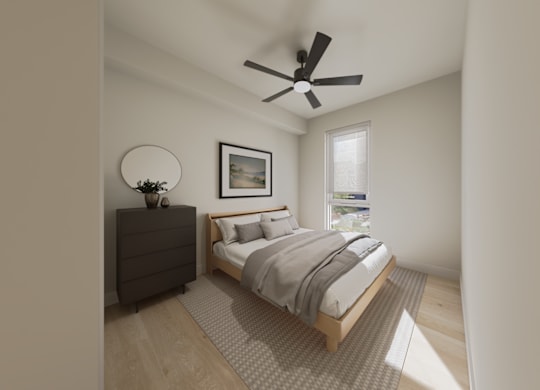 A bedroom with a bed, dresser, and a ceiling fan.