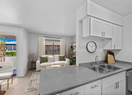 A modern kitchen with a grey countertop and white cabinets.