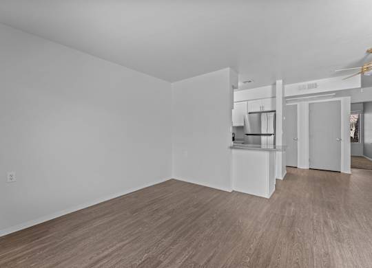 A spacious room with wooden flooring and white walls.