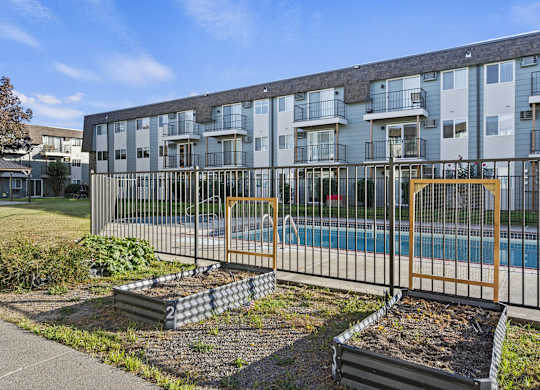an apartment building with a pool behind a fence