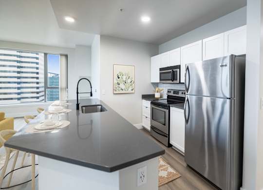 A modern kitchen with a black countertop and stainless steel appliances.