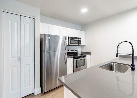 A modern kitchen with a stainless steel refrigerator, oven, and microwave.