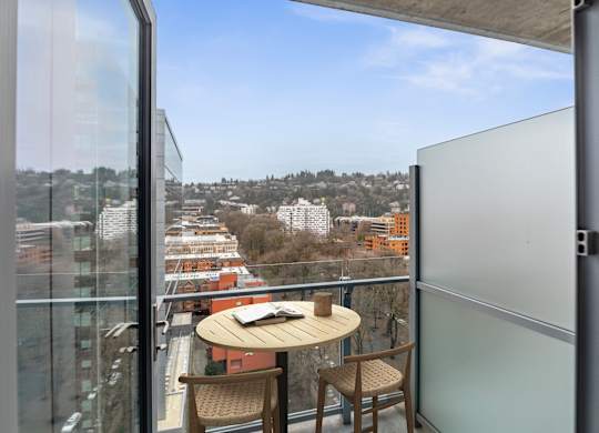 A balcony with a table and chairs overlooking a cityscape.