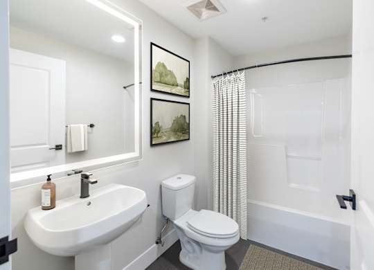 A white bathroom with a toilet, sink, and shower.
