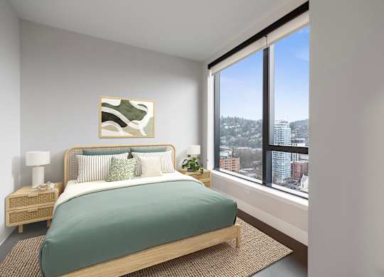A bedroom with a bed, nightstand, and a window overlooking a cityscape.