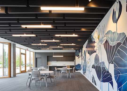 A room with a mural of leaves on the wall and a table with chairs.