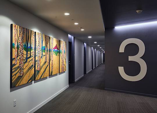 A hallway with a large number 3 on the wall and paintings on the wall.