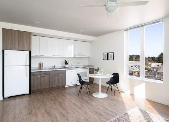 A kitchen with a white fridge, white table and black chairs.