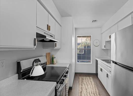 A kitchen with white cabinets and a black counter top.