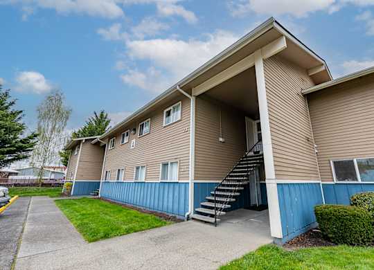A beige and blue apartment building with a staircase leading to the entrance.