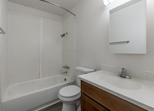 A white bathroom with a toilet, sink, and bathtub.