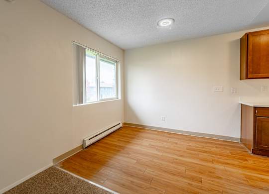 A room with a window and a wooden floor.