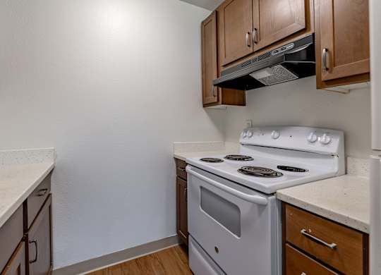 A white stove in a kitchen with wooden cabinets.