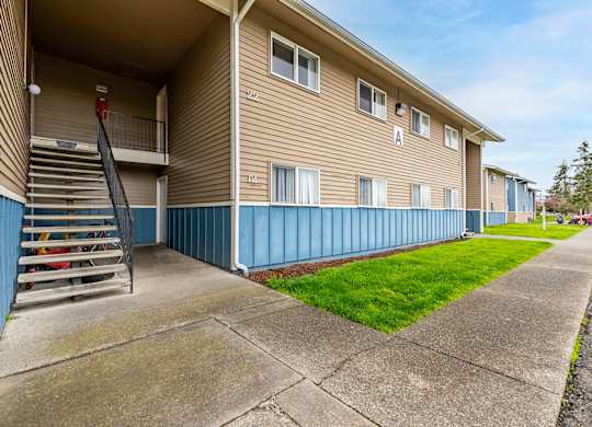 Apartment building with a blue stripe on the side and a staircase leading to the second floor.
