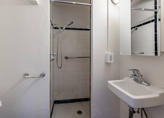 A white sink is mounted on a wall next to a white toilet in a small bathroom.