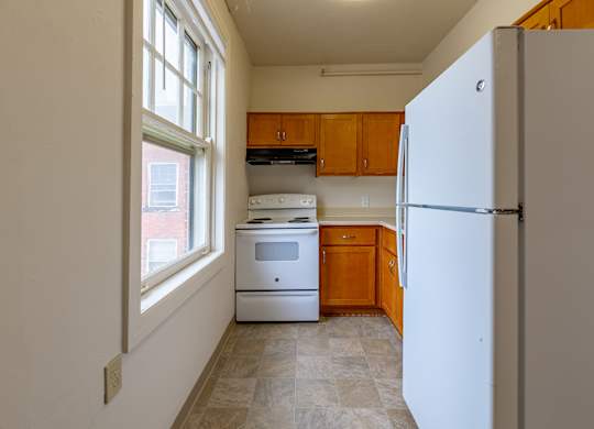 A kitchen with a white fridge and a window.