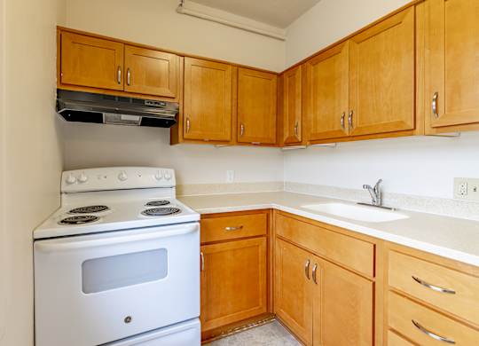 A white stove in a kitchen with wooden cabinets.
