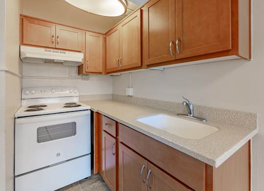 A kitchen with a white stove and wooden cabinets.