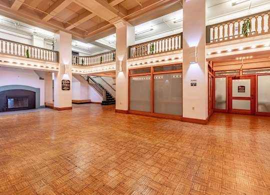 A large room with a wood floor and a fireplace.